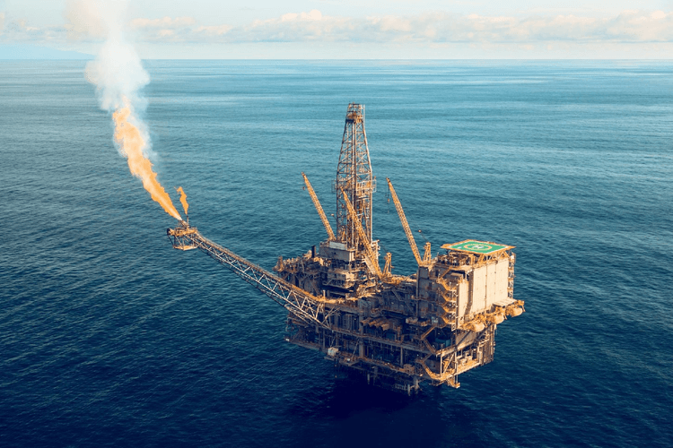 An oil and gas platform in the ocean with a flare stack in operation, showcasing the energy sector's offshore production and safety measures in action.