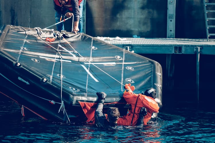 Participants practising water survival skills by boarding a life raft, demonstrating real-world safety training in emergency preparedness.