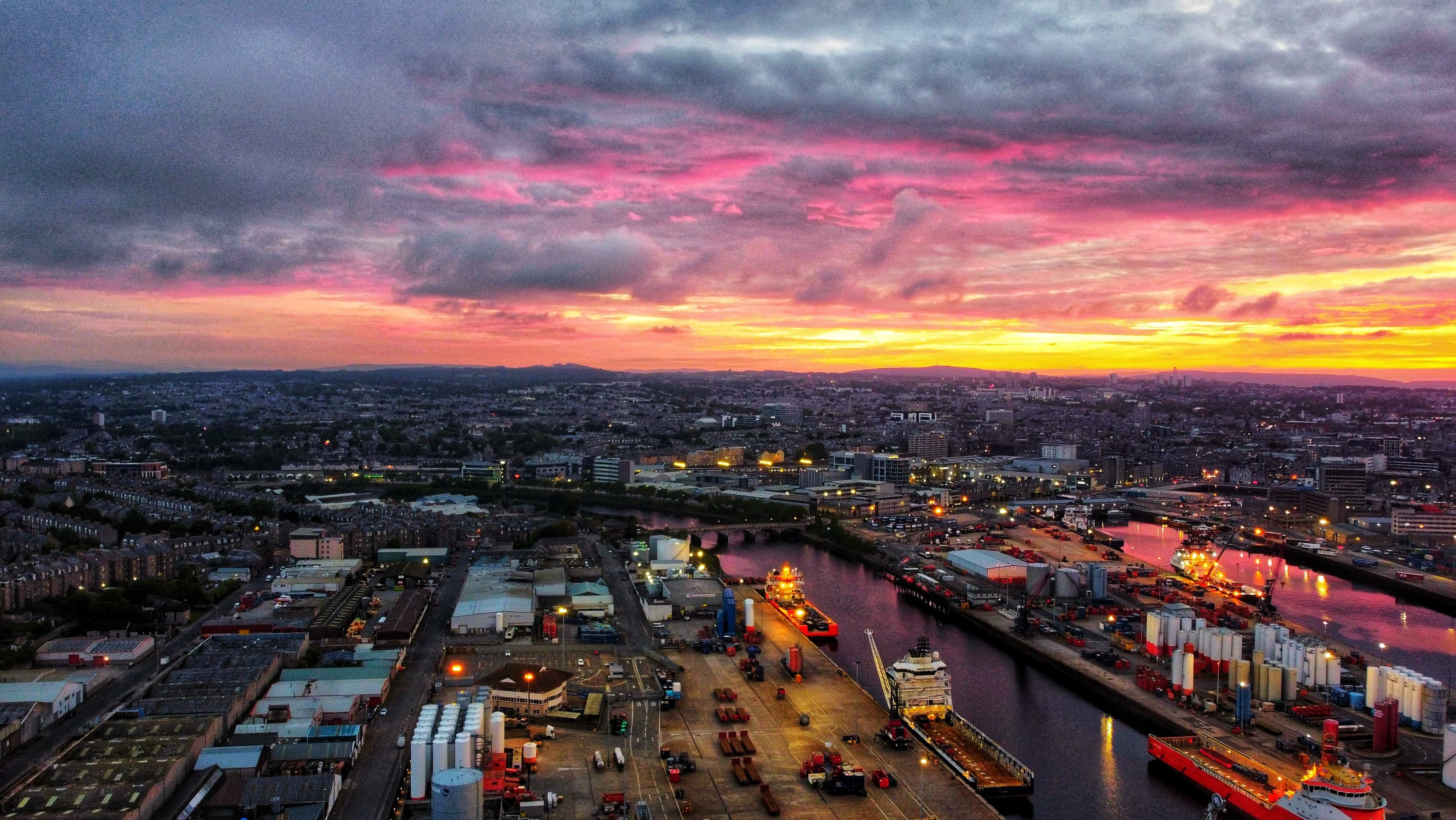 Ariel shot of A vibrant sunset over Aberdeen's bustling port, highlighting the city's role as a key hub for maritime and offshore industries.