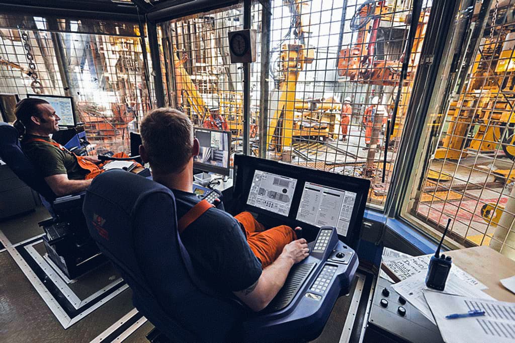Two operators in a control room monitoring and managing offshore machinery, highlighting precision and expertise in operational safety.